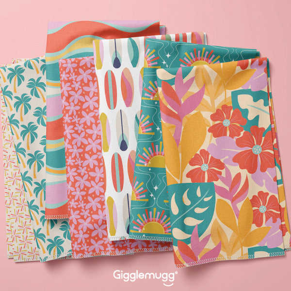 An assortment of folded fabric showing patterns from the 'Sun Lover' surface pattern design collection. Patterns are beach and surf themed.