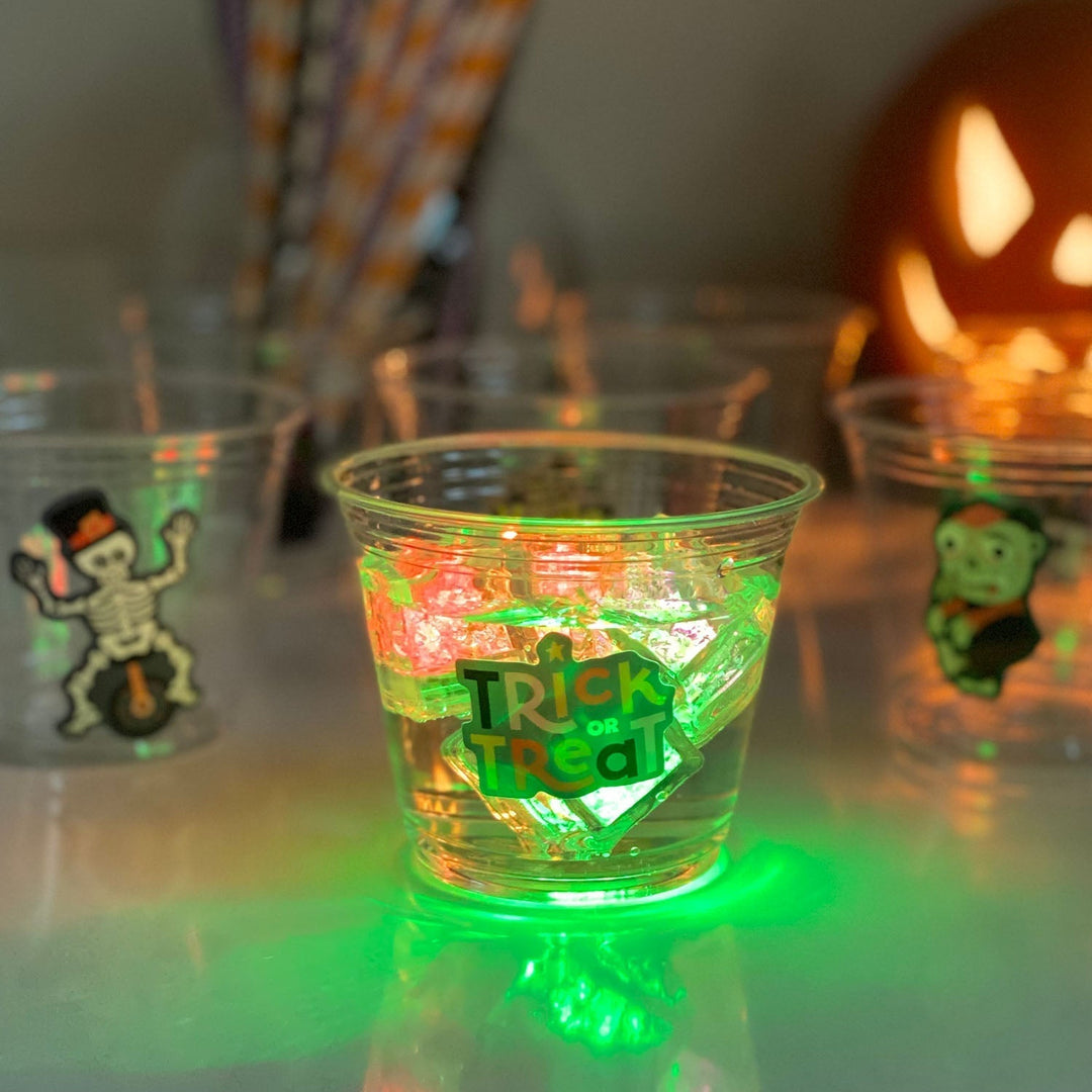 A glowing Halloween party cup decorated with a halloween sticker.