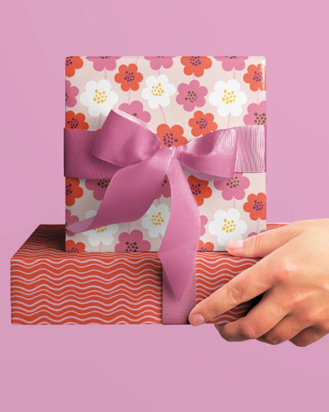 Gifts wrapped in coordinating wrapping paper, with one floral pattern and one a wavy stripe.