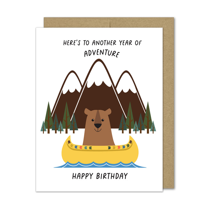 Birthday card with bear in a canoe and mountain background on a Kraft envelope.