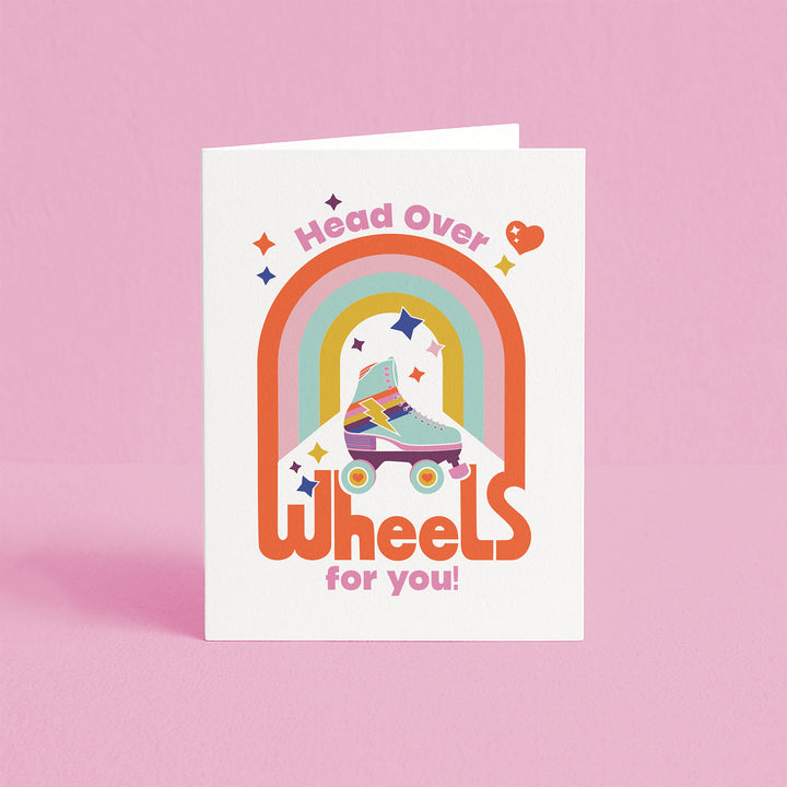 Greeting card with rainbow and roller skates design on a pink background