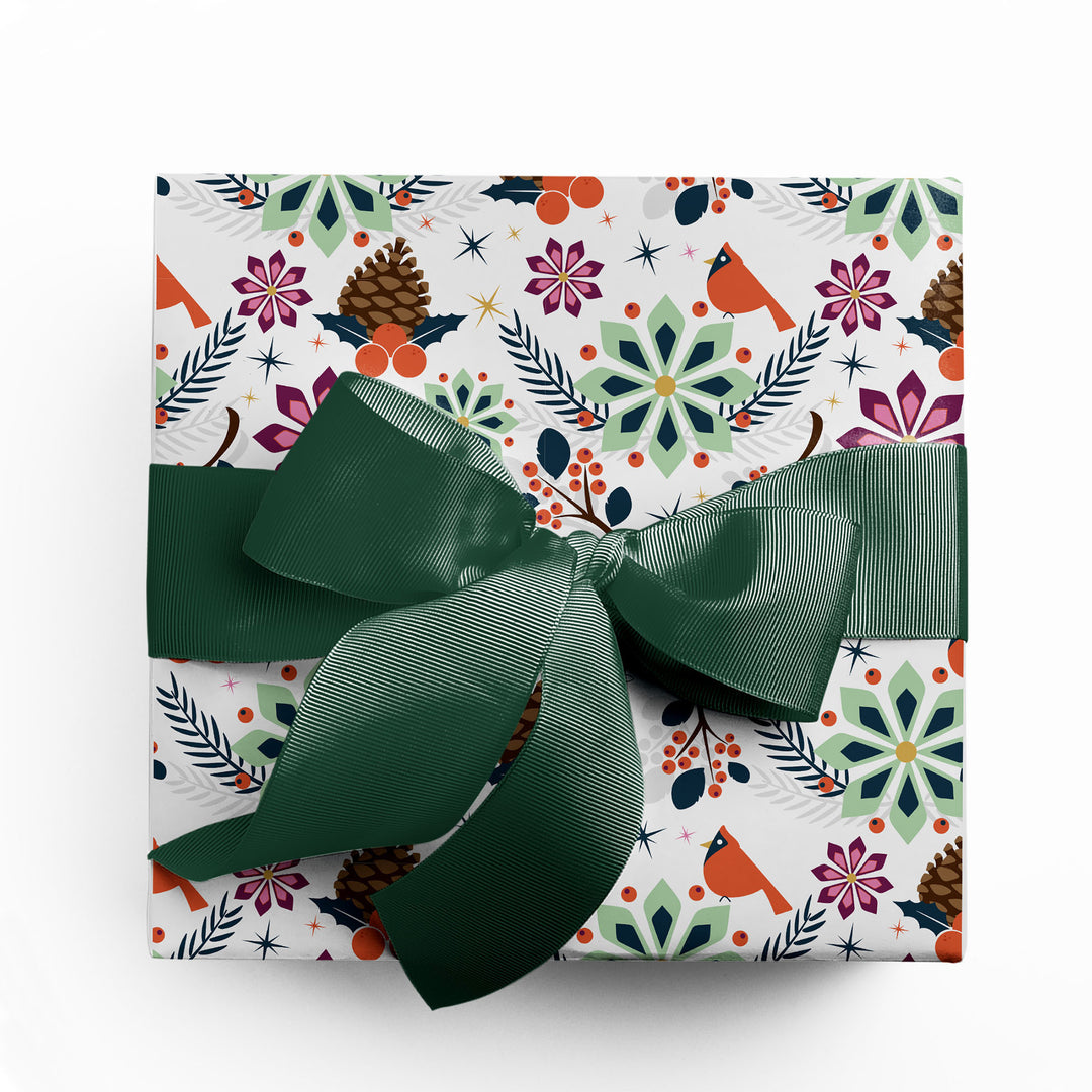 Christmas gift wrapped in modern, holiday poinsettia wrapping paper with green ribbon by Gigglemugg.