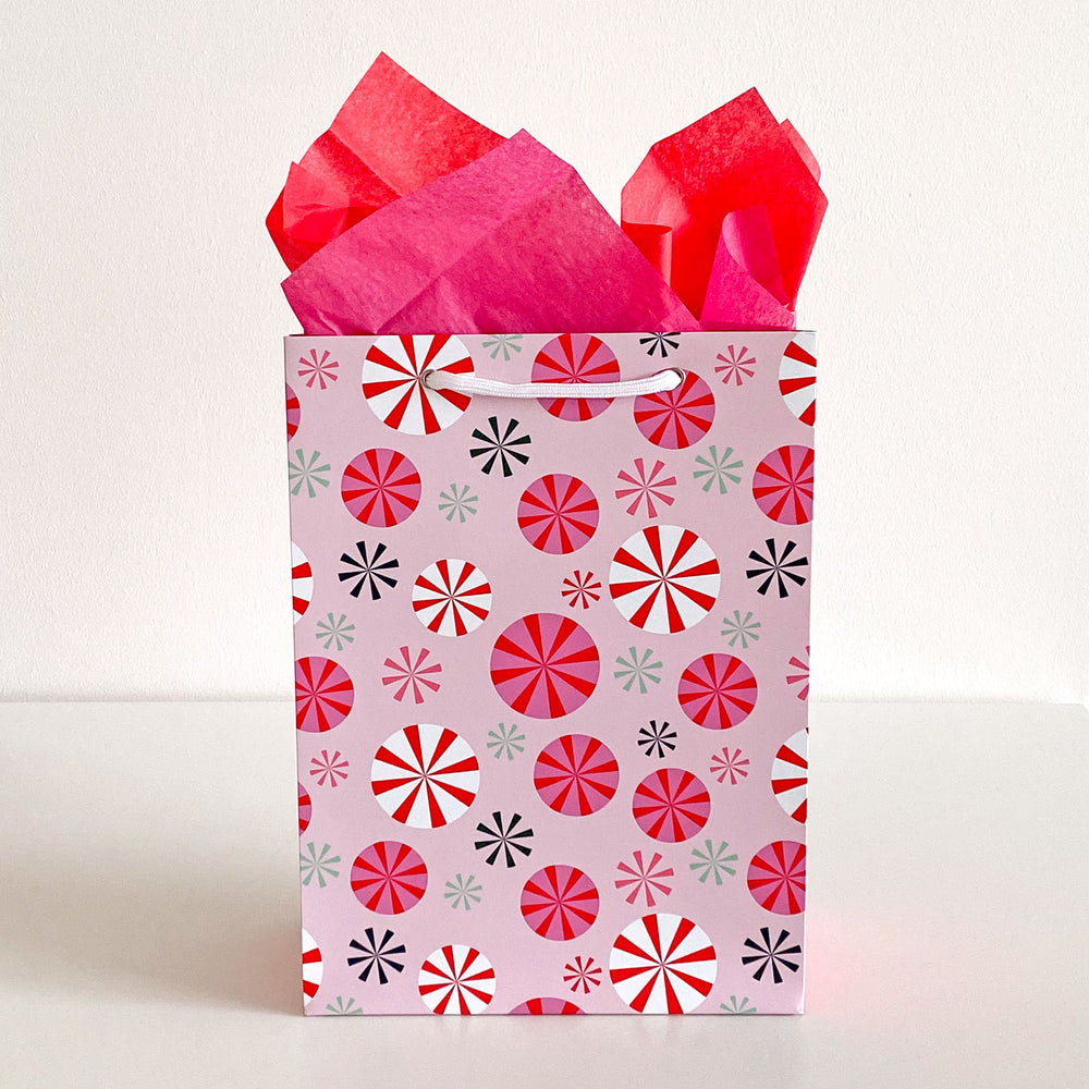 Gift bag with a modern peppermint pattern and red tissue paper on a white background