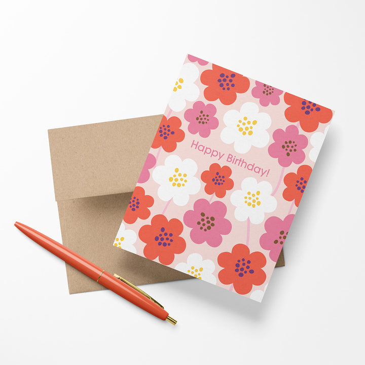 Floral birthday card with colorful flowers shown with an envelope and pen.