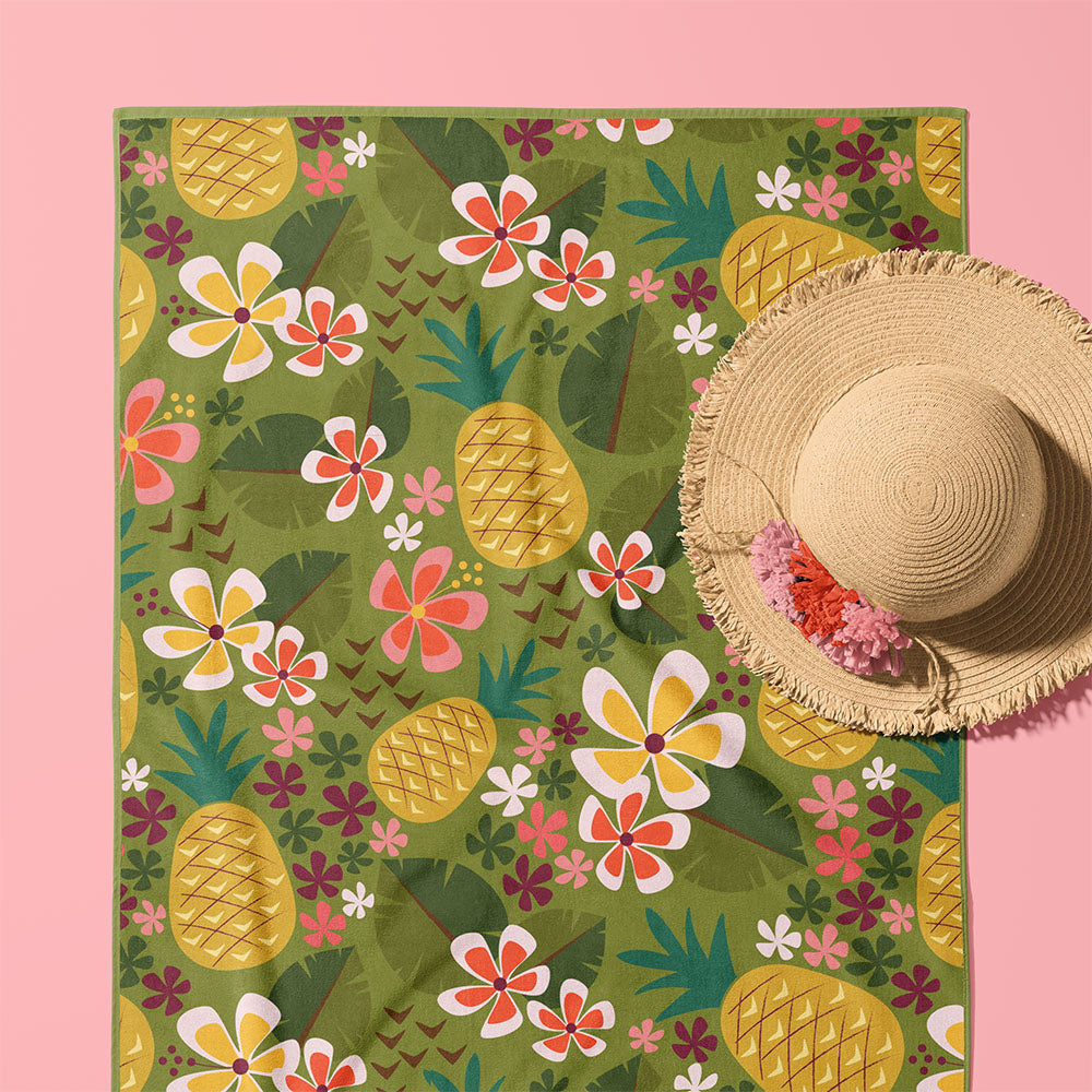 Tropical pineapple patterned beach towel with a straw beach hat on a pink background by ©Gigglemugg